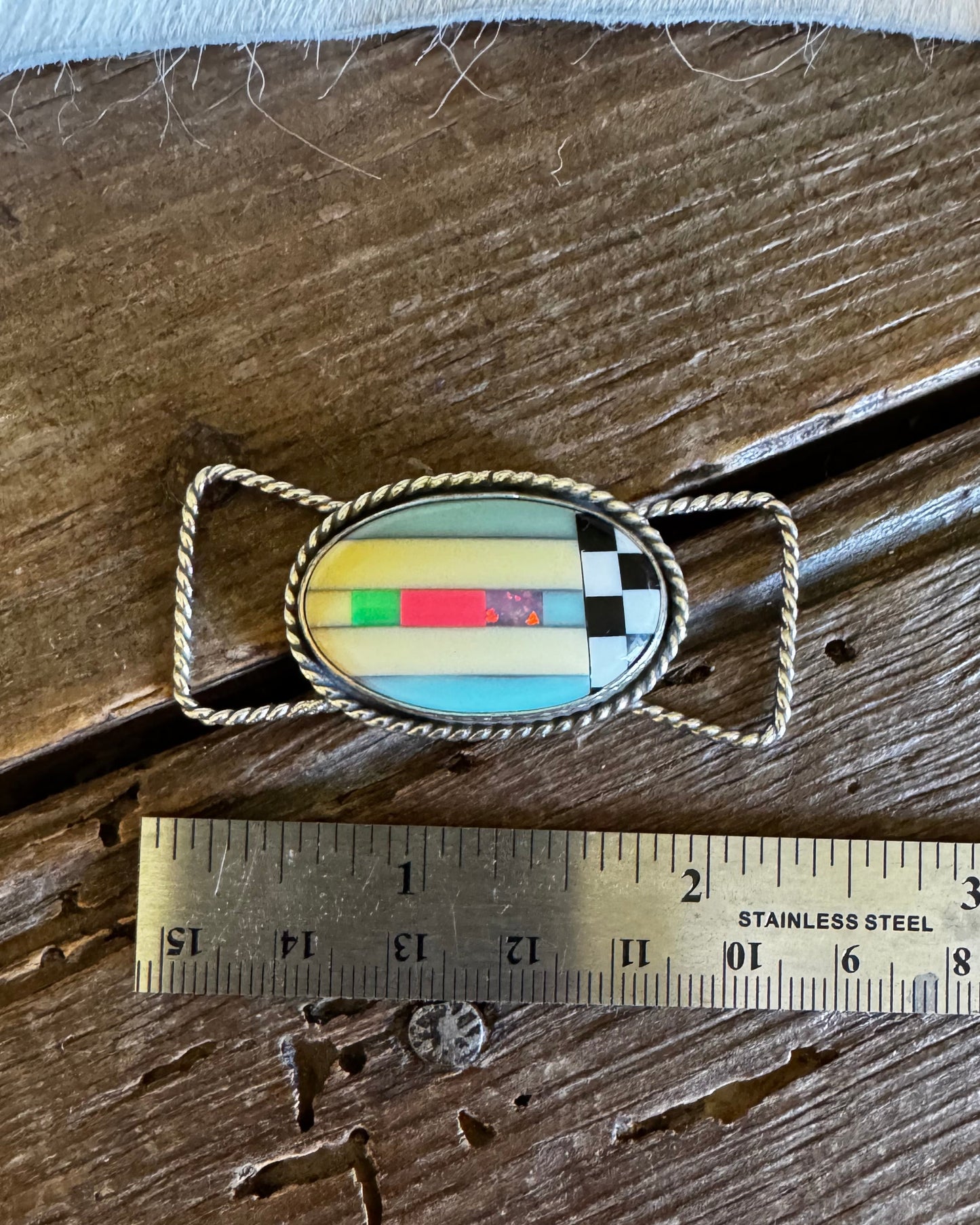 twilly slide with colorful design on a wooden surface next to a ruler for scale.