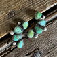 Turquoise stone and silver earring on a wooden surface