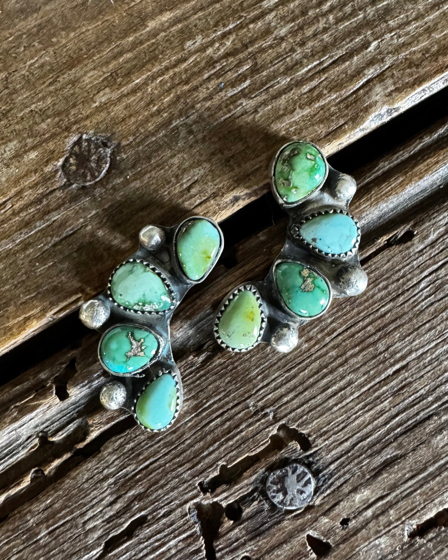 Turquoise stone and silver earring on a wooden surface