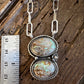 Necklace with a double pendant on a wooden surface next to a ruler for scale.