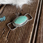 Turquoise stone pendant on a wooden surface with white fur