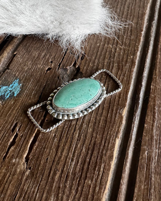 Turquoise stone pendant on a wooden surface with white fur