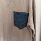 Close-up of a beige corduroy garment with a blue denim pocket detail.