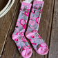 Pair of pink and gray patterned socks on a wooden surface with a cowhide rug.