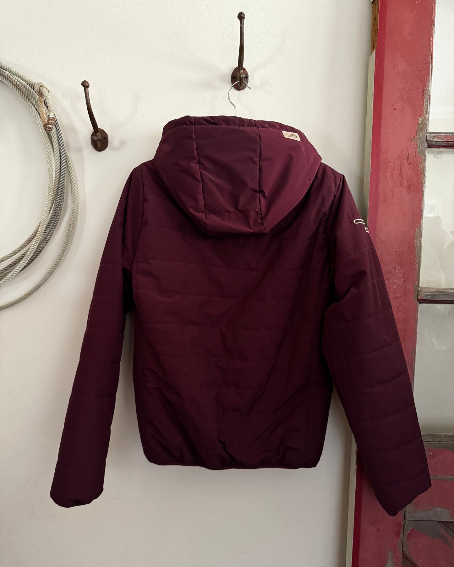 Maroon jacket on a white surface with a red frame in the background
