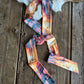 Colorful patterned ribbon scarf on a wooden surface with a cowhide rug.