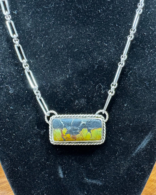 Necklace with a rectangular pendant on a black velvet stand.