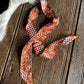 Orange paisley scarf on a wooden surface with animal fur in the background
