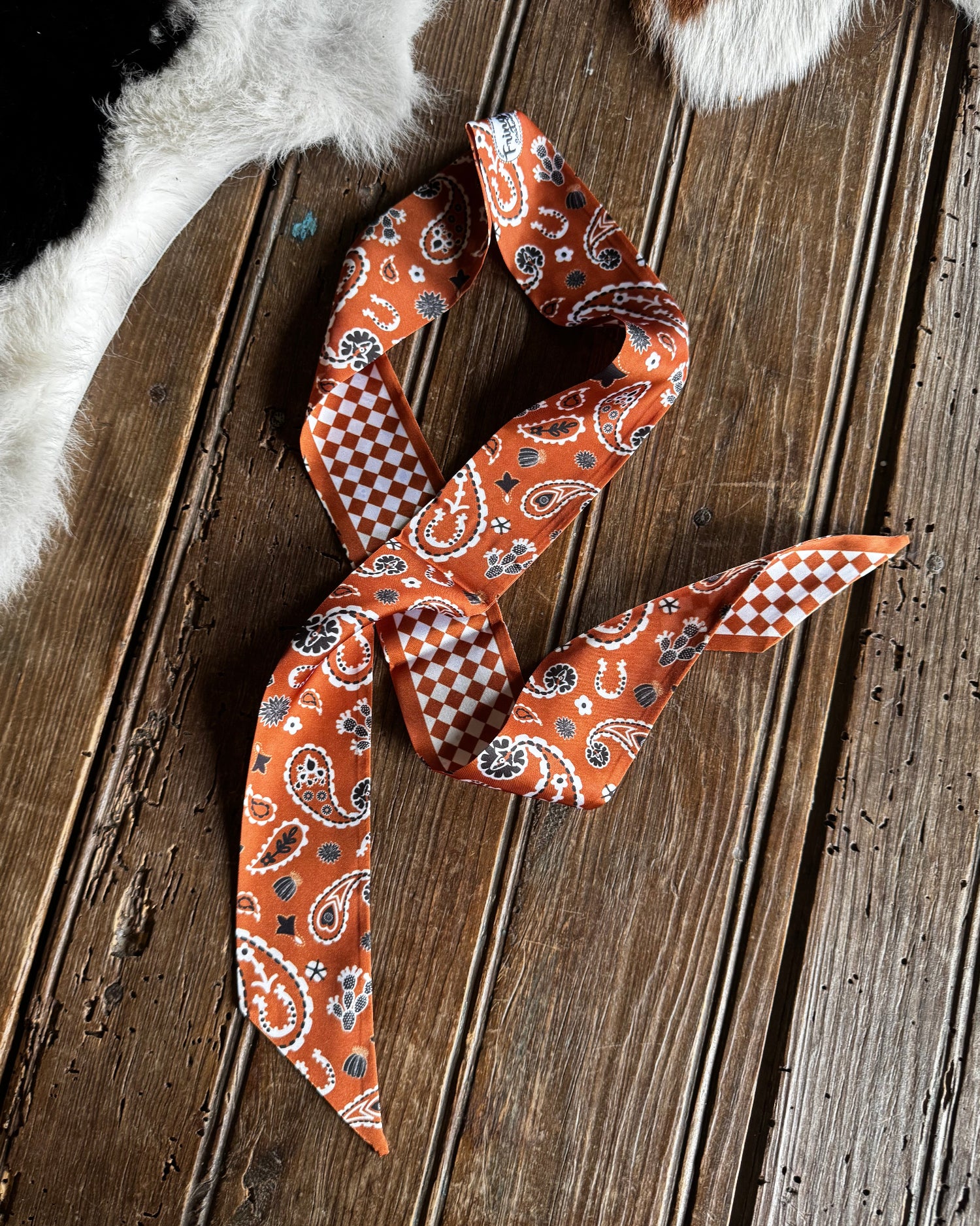 Orange paisley scarf on a wooden surface with animal fur in the background