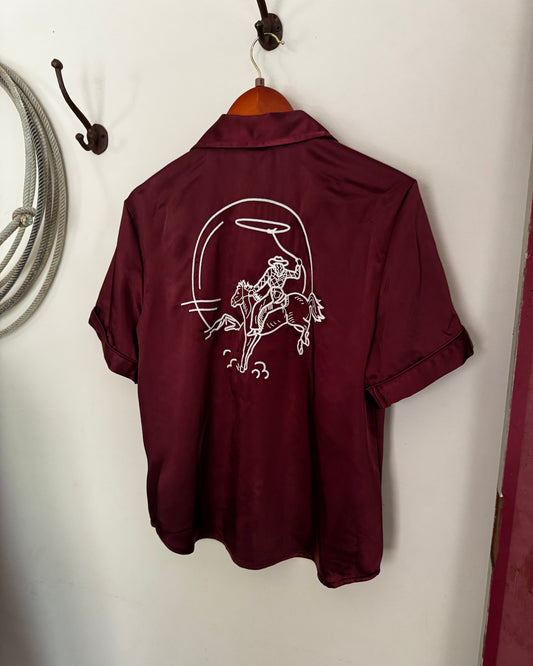 Maroon shirt with white graphic design on a white surface