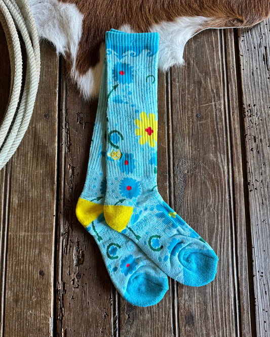 Pair of blue socks with floral designs on a wooden surface