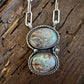 Silver necklace with two turquoise stone pendants on a wooden surface