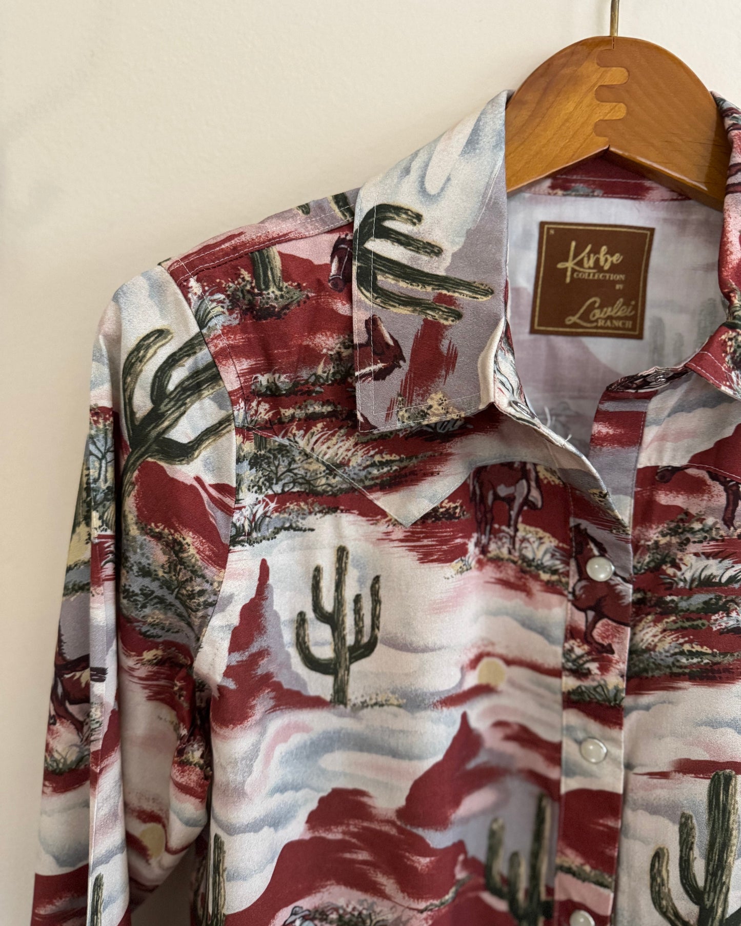 Floral patterned shirt with cactus design on a hanger against a white background
