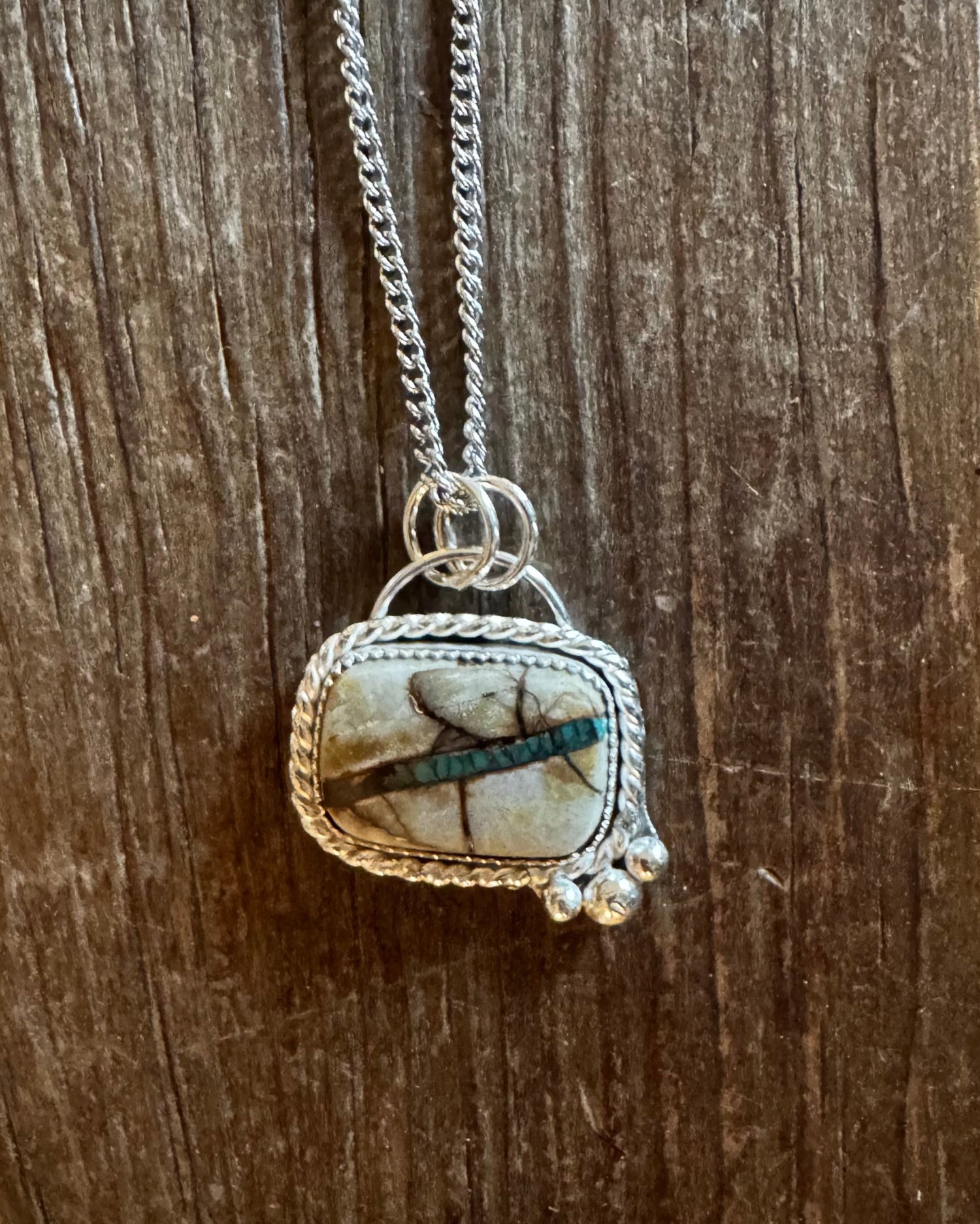 Necklace with a pendant featuring a stone and dragonfly design on a wooden surface
