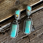 Pair of turquoise stone earrings on a wooden surface