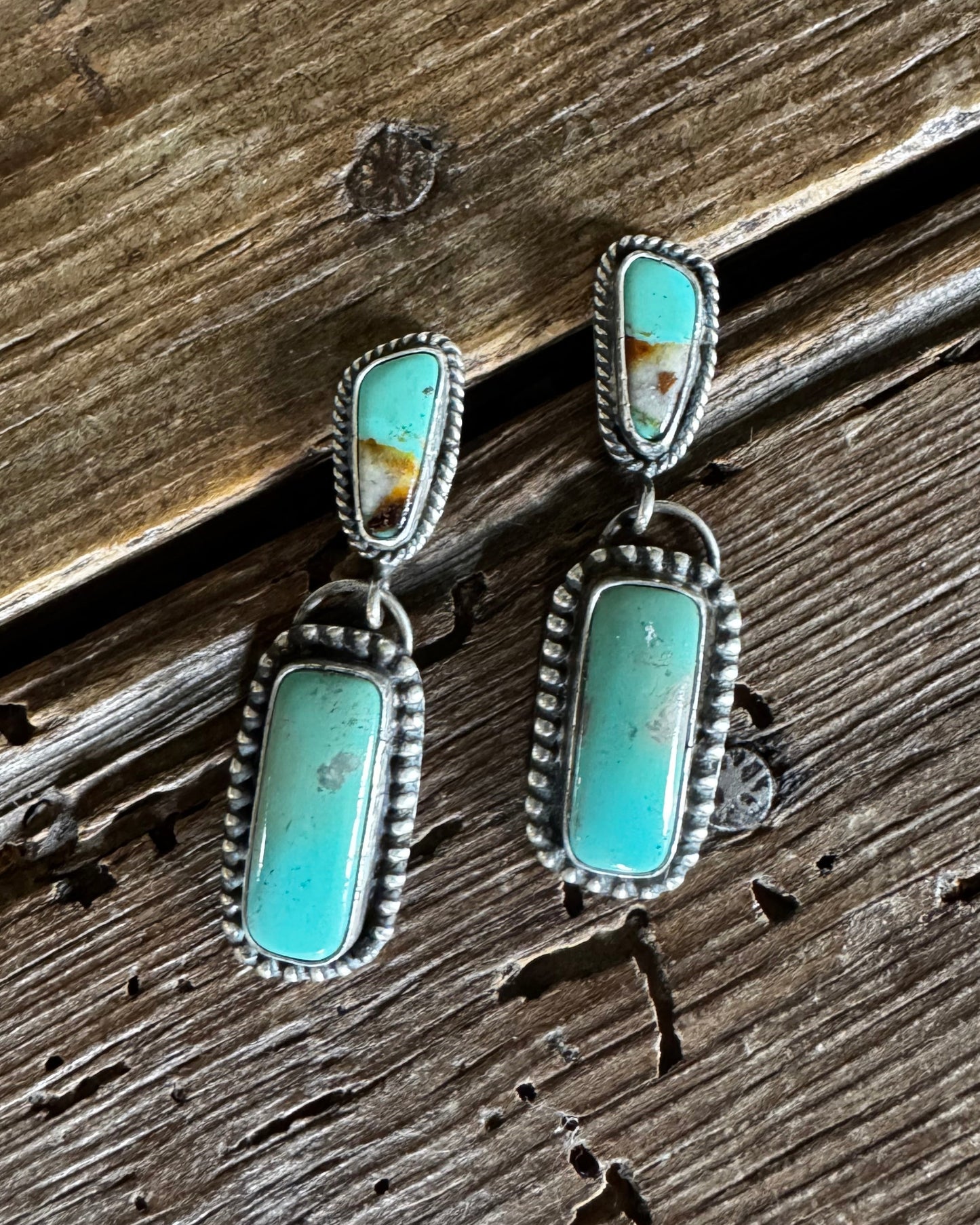 Pair of turquoise stone earrings on a wooden surface