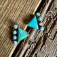 Turquoise triangle-shaped earrings on a wooden surface