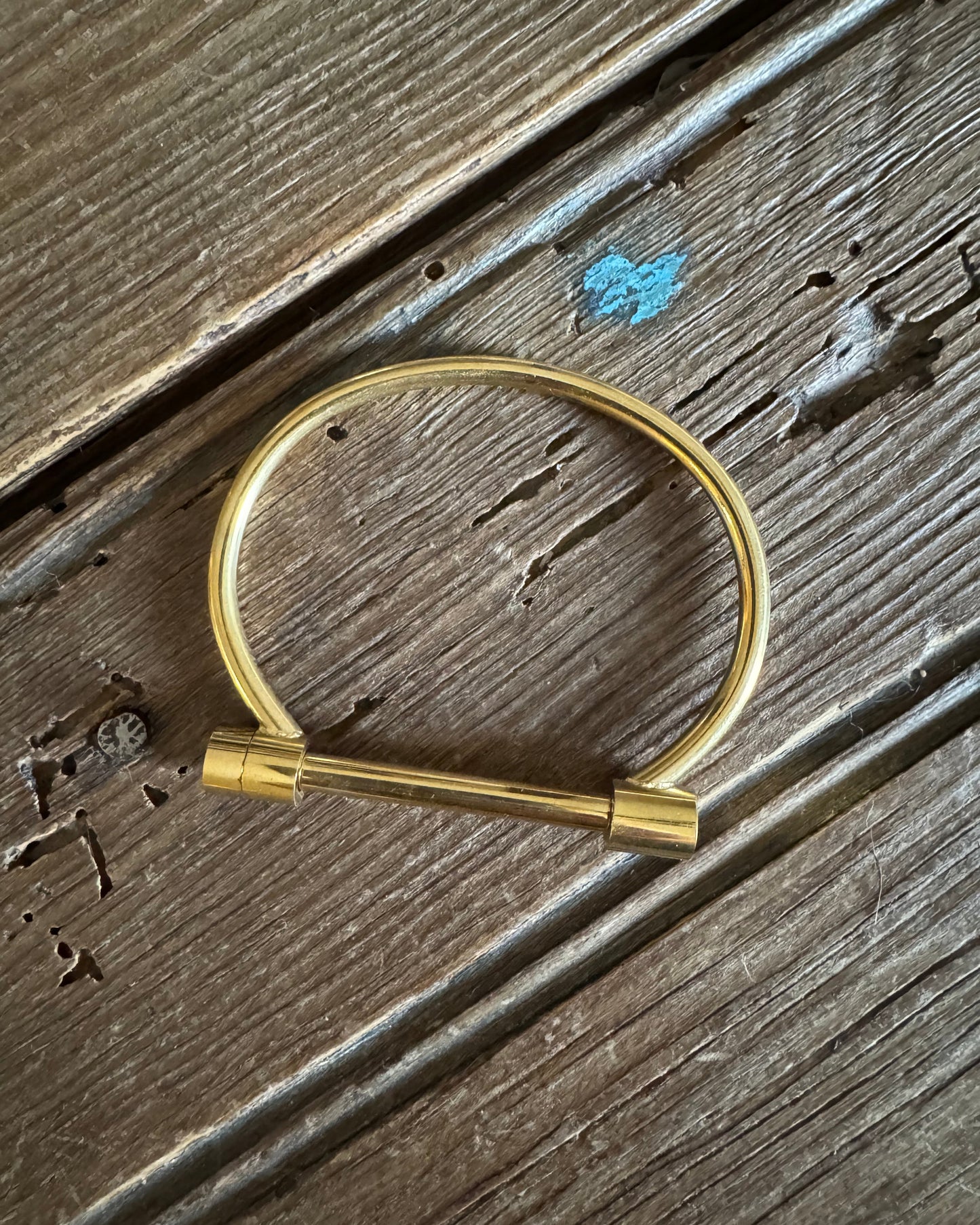 Gold plated screw closure cuff bracelet on rustic wood background