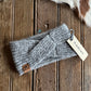 Gray knit headband with Ariat tag on a wooden surface