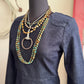 Mannequin wearing a denim dress with layered necklaces on a neutral background
