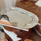 Silver tray on a wooden surface with a brown leather chair and cowhide rug in the background