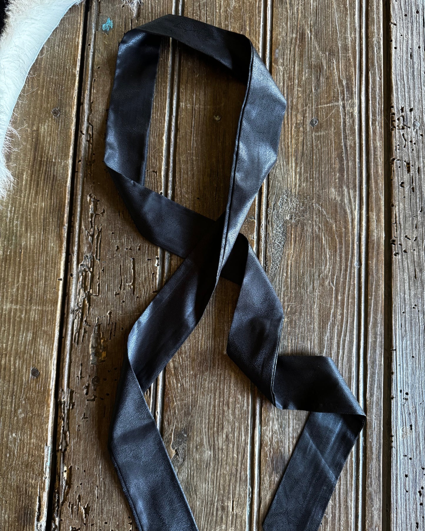 Black satin ribbon on a wooden surface