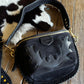 Black handbag with gold accents on a wooden surface