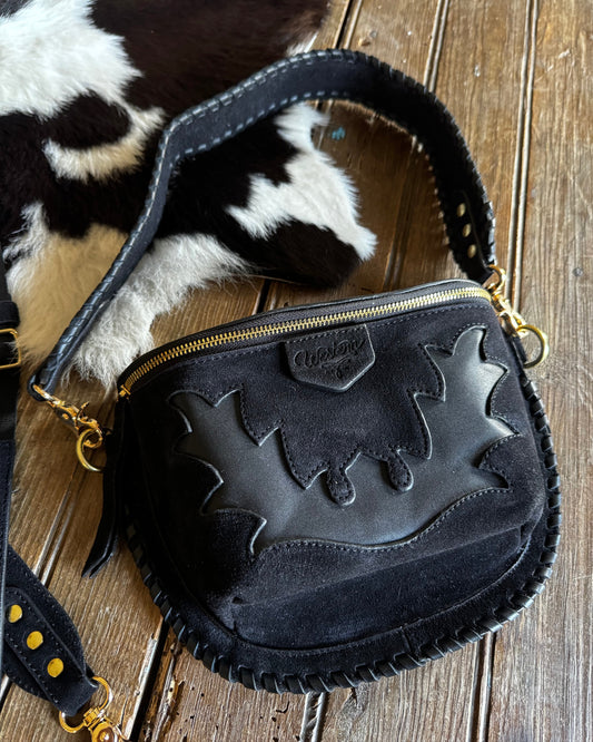 Black handbag with gold accents on a wooden surface