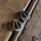 Pair of silver earrings with black stones on a wooden surface