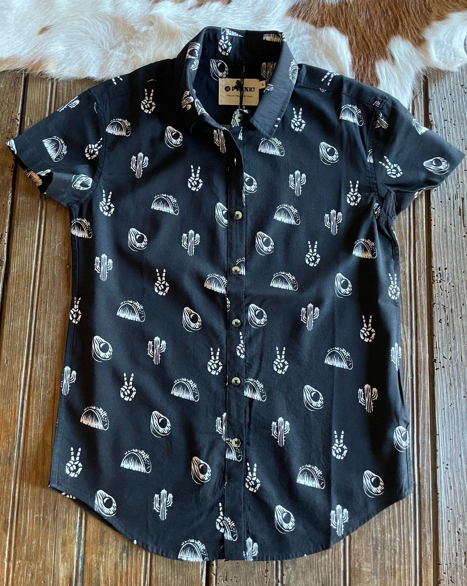 flat lay of short sleeved button up shirt with tacos, cacti, avacados and skeleton peace signs