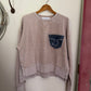 Brown sweatshirt with a logo on a hanger against a white wall.