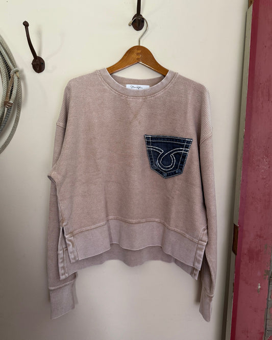 Brown sweatshirt with a logo on a hanger against a white wall.
