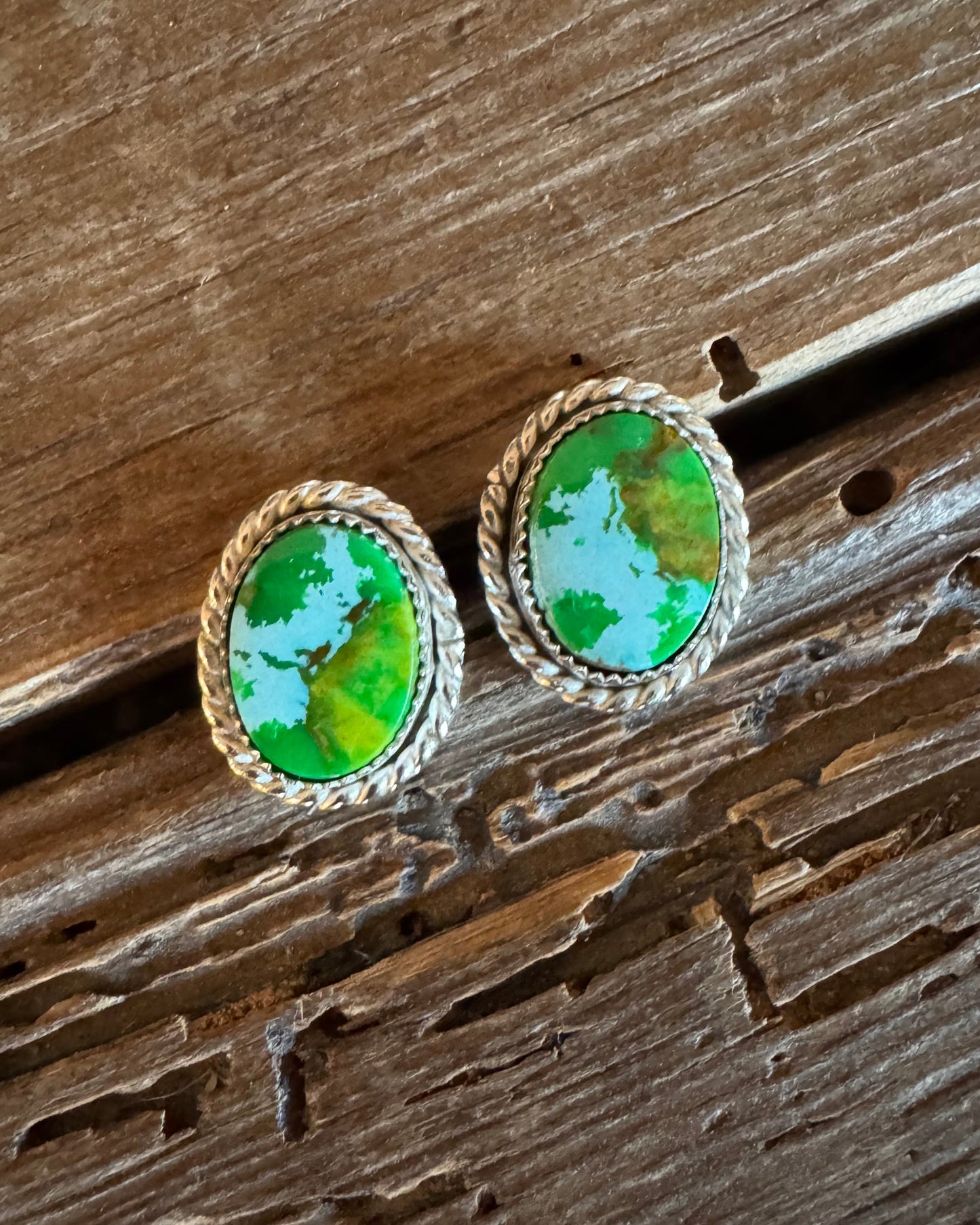 Pair of green gemstone earrings on a wooden surface