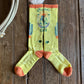 Pair of yellow socks with orange accents on a wooden surface
