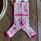 Pair of pink socks with floral patterns on a wooden surface