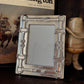 Decorative picture frame with a cowboy theme in front of a book titled 'Ned Buntline's Life of Buffalo Bill' and a cowboy hat.