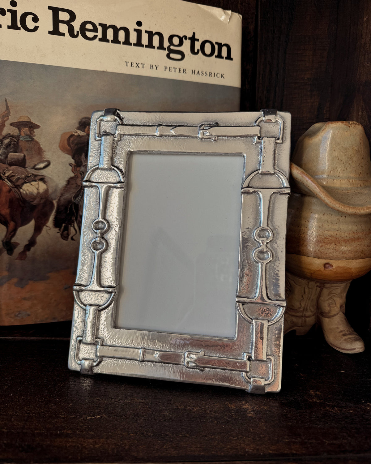 Decorative picture frame with a cowboy theme in front of a book titled 'Ned Buntline's Life of Buffalo Bill' and a cowboy hat.