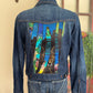 Blue denim jacket with colorful coyote design on the back, displayed on a mannequin against a neutral background.