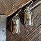 Pair of earrings with stone inlays on a wooden surface with a ruler for scale.