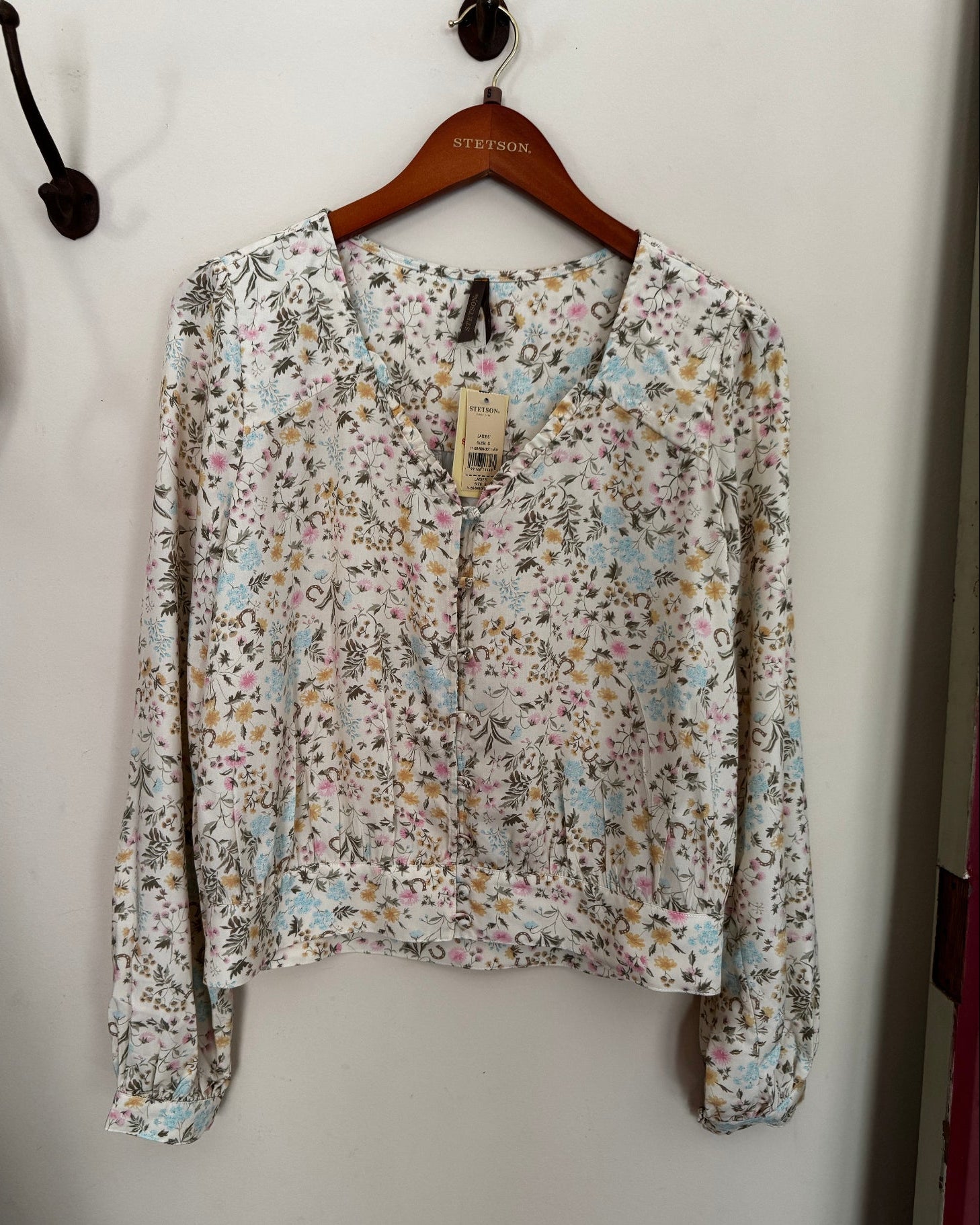 Floral-patterned shirt on a hanger against a white background