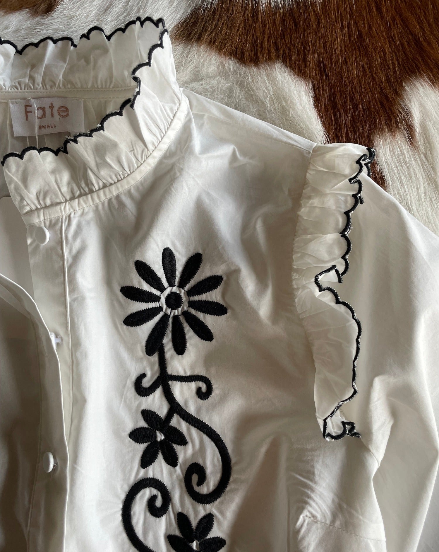 Close up of black embroidery on white blouse