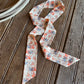 Ribbon scarf with horses laying on a rustic wood background with a rope