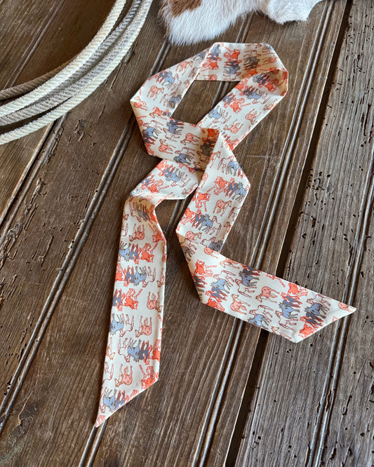 Ribbon scarf with horses laying on a rustic wood background with a rope