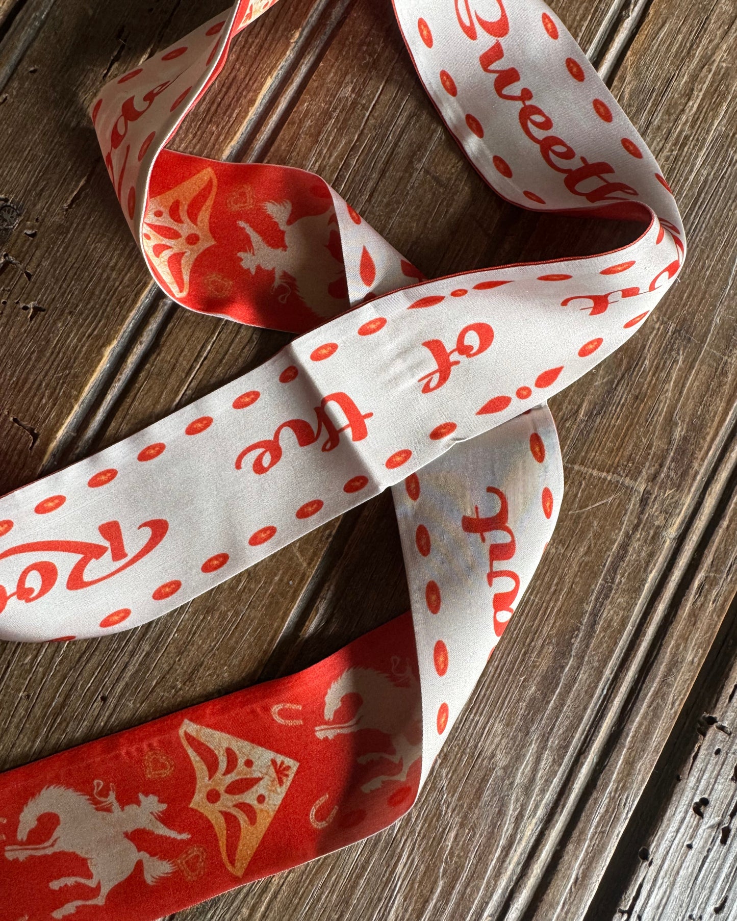 Decorative ribbon with red text and patterns on a wooden surface