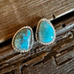 Turquoise stone earrings on a wooden surface