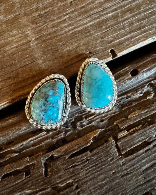 Turquoise stone earrings on a wooden surface