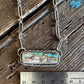 Necklace with a pendant next to a ruler on a wooden surface