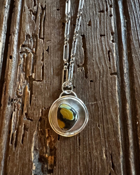Necklace with a circular pendant on a wooden surface