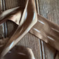 Brown ribbon scarf with white leaf patterns on a wooden surface