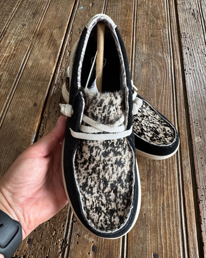 Person holding a patterned shoe against a wooden background